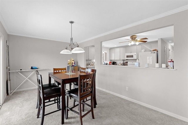 carpeted dining room with ceiling fan and ornamental molding