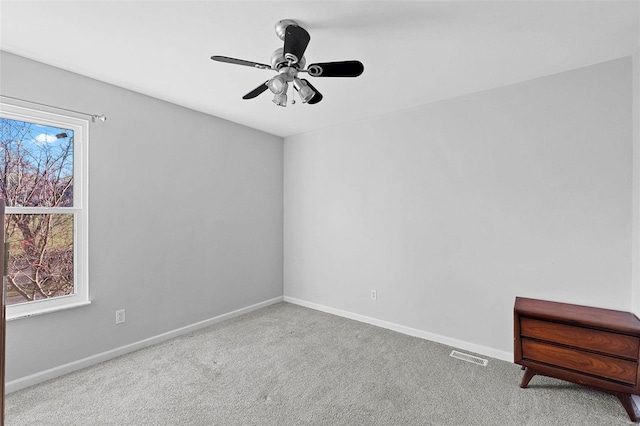 carpeted spare room featuring ceiling fan and a wealth of natural light