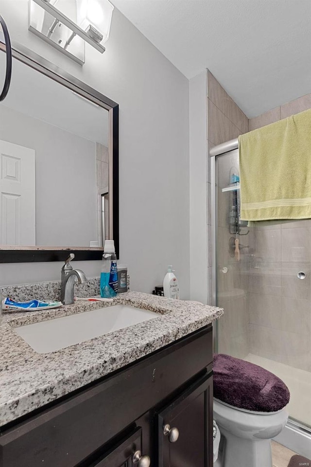 bathroom featuring vanity, toilet, and a shower with door