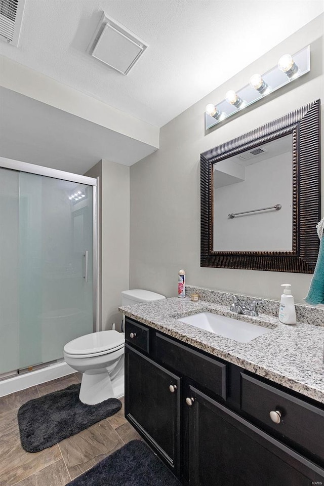 bathroom featuring vanity, toilet, and an enclosed shower