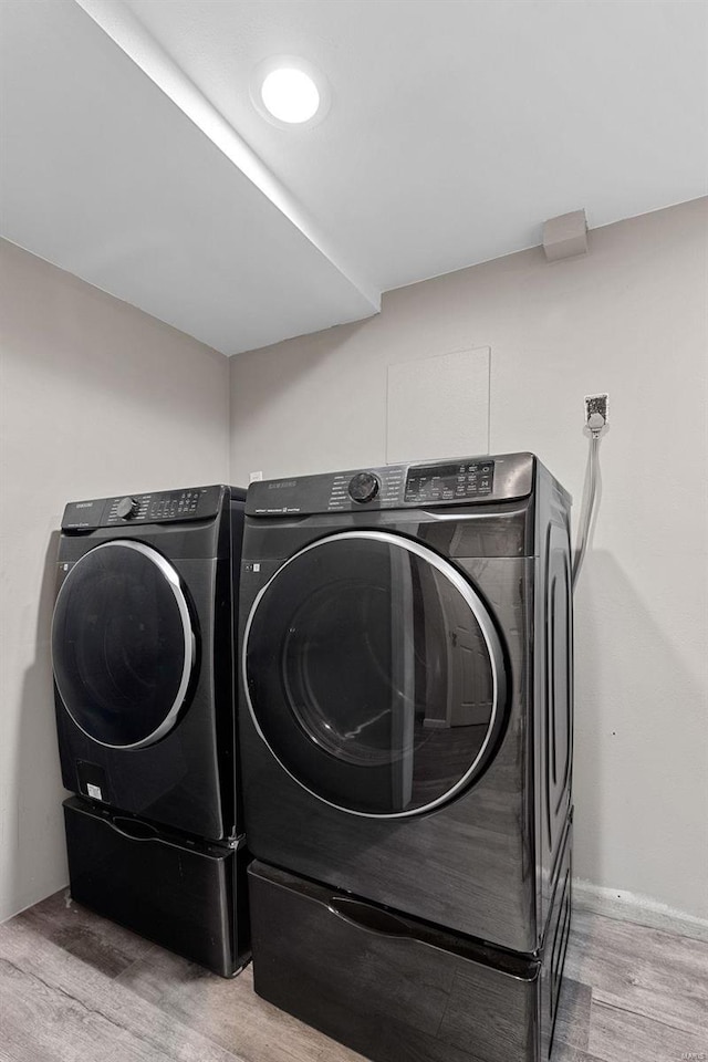 clothes washing area featuring light wood-type flooring and washing machine and clothes dryer