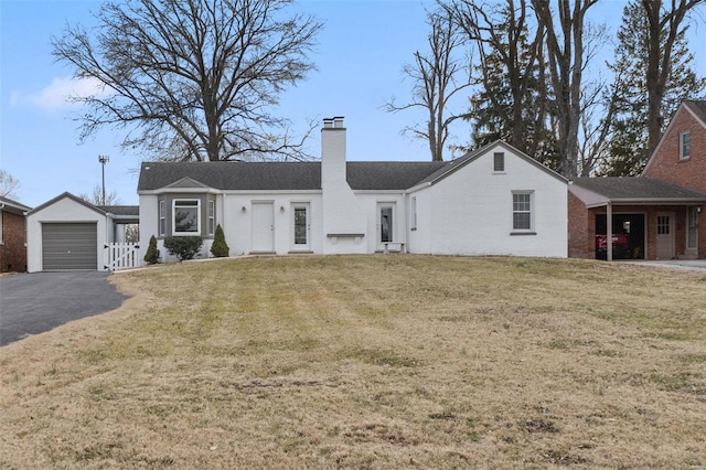 ranch-style house with brick siding, a front lawn, a chimney, an outdoor structure, and driveway