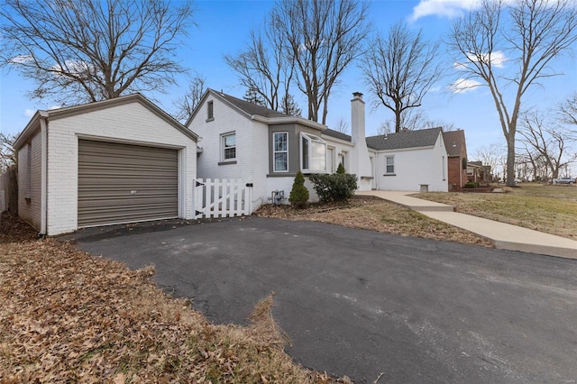 view of front of house with a garage, brick siding, driveway, and a chimney