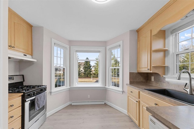 kitchen with light brown cabinets, a baseboard heating unit, stainless steel range with gas cooktop, under cabinet range hood, and a sink