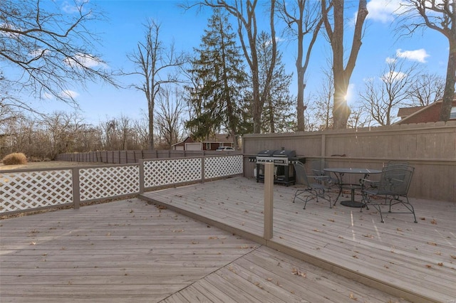 deck with outdoor dining area, a grill, and fence