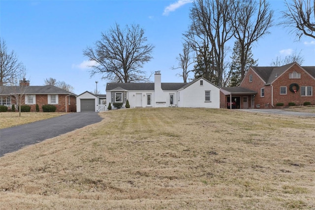 ranch-style house featuring driveway, a chimney, an outdoor structure, a front lawn, and a garage