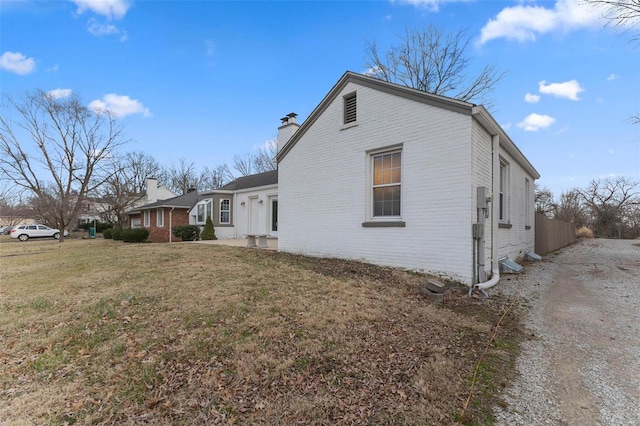 view of property exterior featuring a yard, brick siding, and a chimney