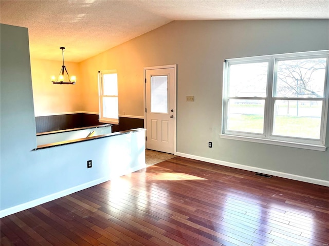 interior space with a chandelier, pendant lighting, dark hardwood / wood-style flooring, and vaulted ceiling