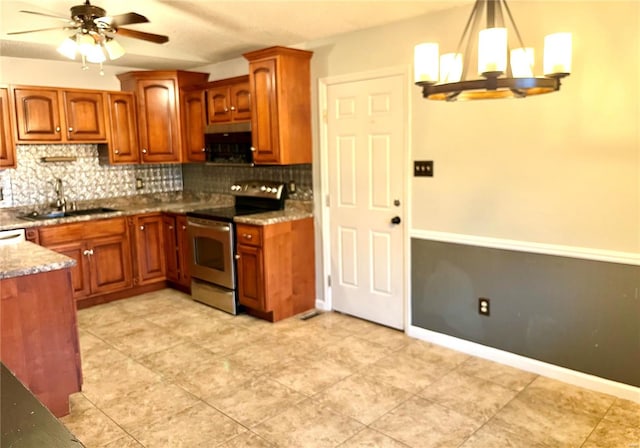 kitchen with ceiling fan with notable chandelier, sink, electric stove, dark stone countertops, and hanging light fixtures