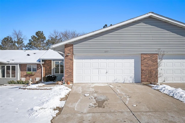 view of front of property featuring brick siding, driveway, and a garage