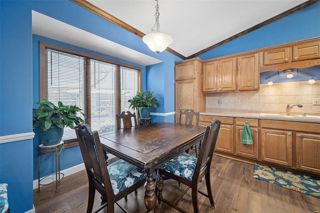 dining space featuring dark wood finished floors, lofted ceiling, crown molding, and baseboards