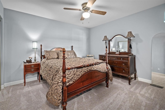 carpeted bedroom featuring arched walkways, ceiling fan, and baseboards