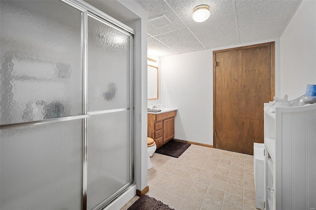 full bath with visible vents, a shower stall, baseboards, vanity, and a paneled ceiling