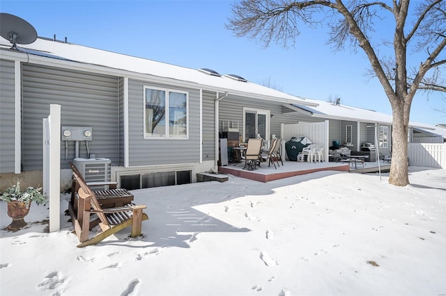 snow covered rear of property with a patio and fence