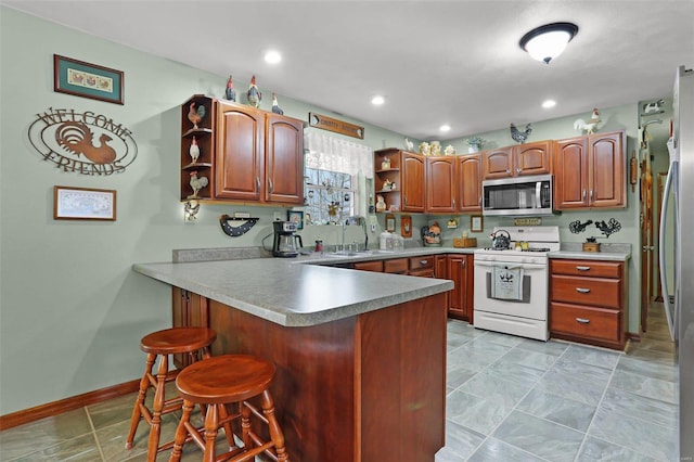 kitchen with a breakfast bar, kitchen peninsula, sink, and appliances with stainless steel finishes