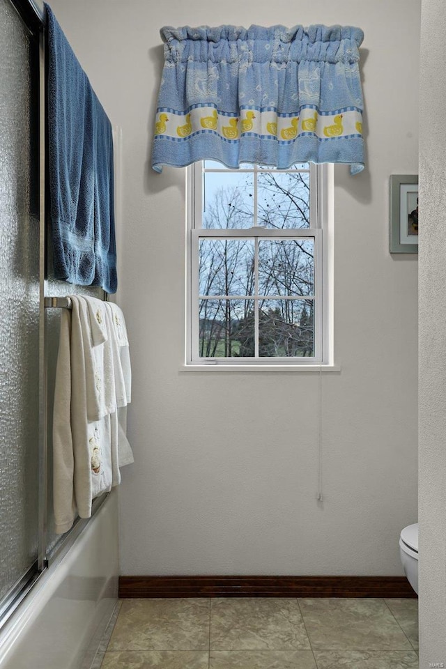 bathroom with tile patterned flooring, toilet, and shower / bath combination with glass door