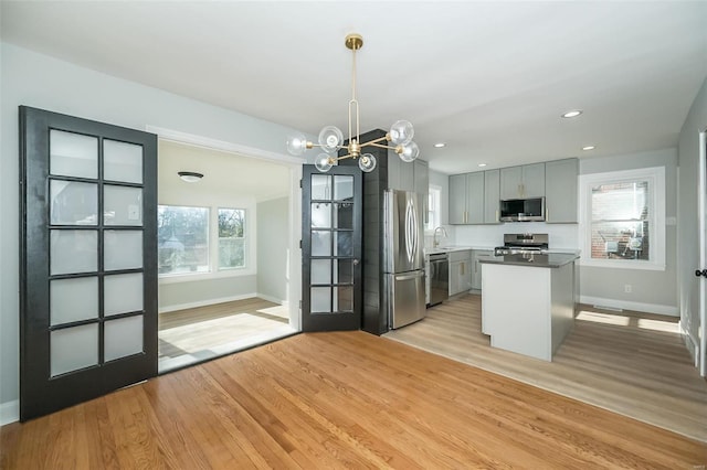 kitchen featuring gray cabinetry, stainless steel appliances, light hardwood / wood-style flooring, a center island, and hanging light fixtures