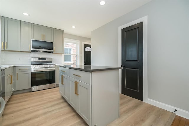 kitchen featuring stainless steel range, decorative backsplash, light wood-type flooring, and a center island