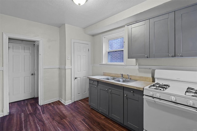 kitchen featuring sink, white range with gas stovetop, dark hardwood / wood-style floors, a textured ceiling, and gray cabinets