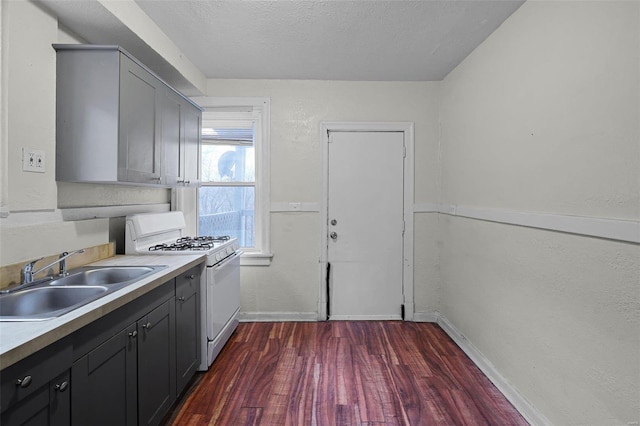 kitchen with white gas range, sink, gray cabinetry, and dark hardwood / wood-style flooring