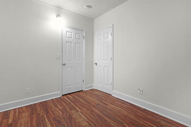 empty room with dark hardwood / wood-style flooring and a textured ceiling