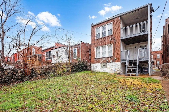 rear view of property featuring a yard and a balcony