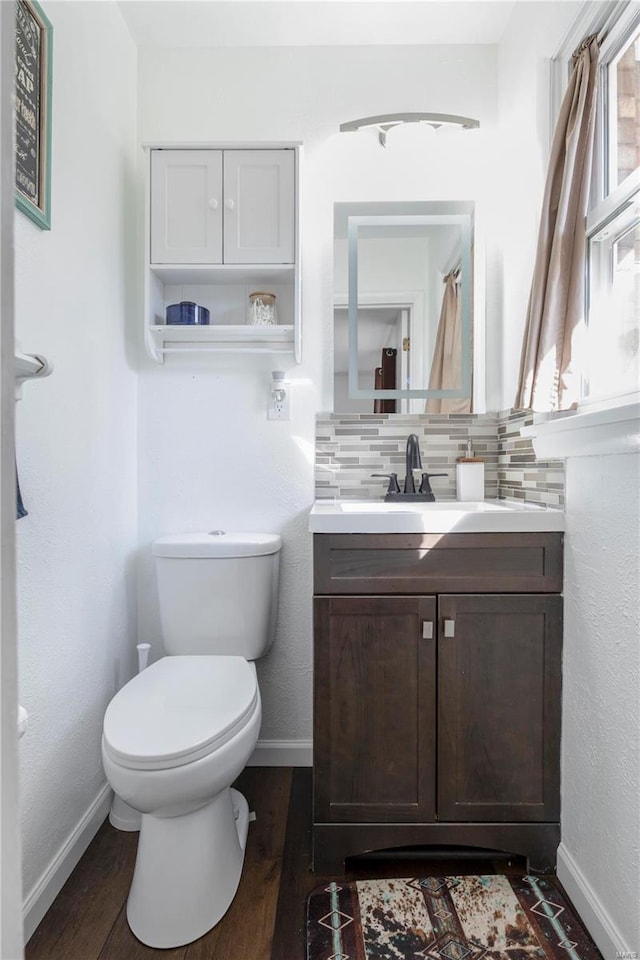 bathroom with decorative backsplash, toilet, wood finished floors, and baseboards