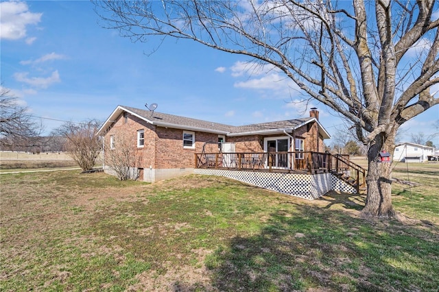 rear view of house with a deck, a lawn, brick siding, and a chimney