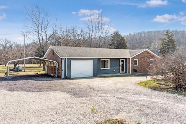 ranch-style house with brick siding, a detached carport, driveway, and an attached garage