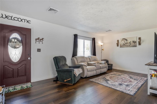 living area featuring visible vents, a textured ceiling, dark wood-type flooring, and baseboards