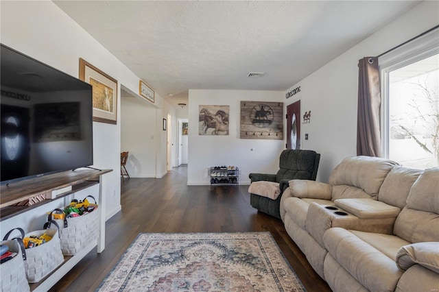 living room featuring visible vents, a textured ceiling, baseboards, and hardwood / wood-style floors