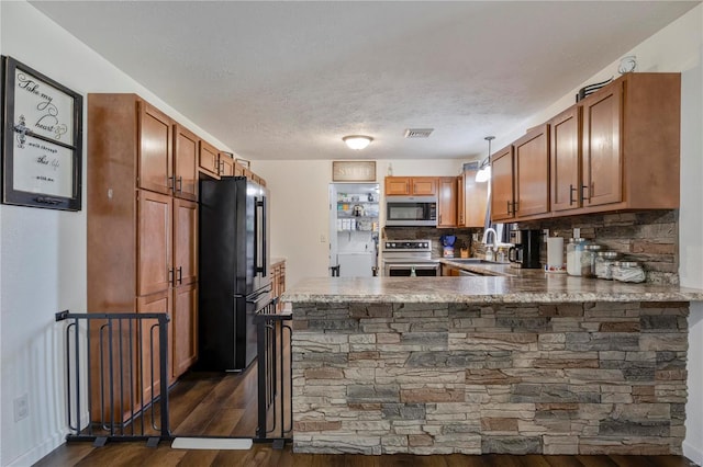 kitchen with visible vents, brown cabinets, appliances with stainless steel finishes, a peninsula, and dark wood-style flooring