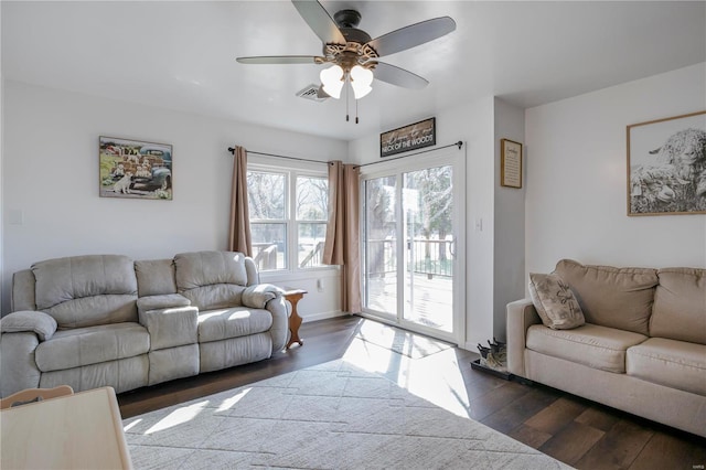 living room featuring ceiling fan, visible vents, and dark wood finished floors