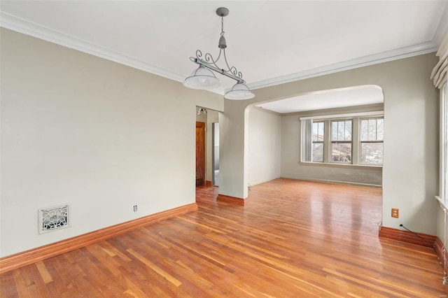 spare room featuring light hardwood / wood-style floors, ornamental molding, and an inviting chandelier