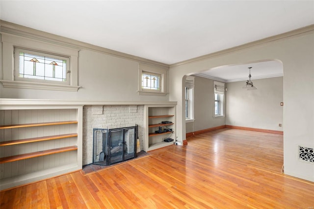 unfurnished living room featuring light hardwood / wood-style floors, ornamental molding, and a fireplace