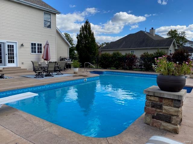 view of swimming pool featuring grilling area, a diving board, and a patio