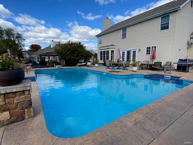 view of swimming pool with a patio, a diving board, and grilling area