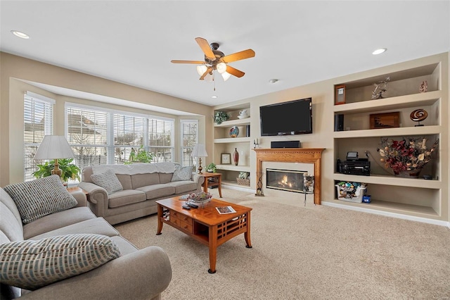 living room with built in shelves, light colored carpet, and ceiling fan