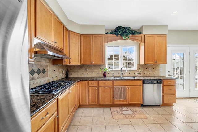 kitchen with appliances with stainless steel finishes, light tile patterned floors, dark stone countertops, and sink