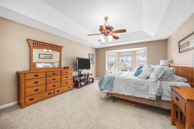 carpeted bedroom featuring ceiling fan and a tray ceiling