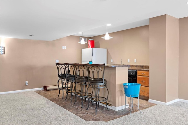 kitchen featuring dark colored carpet, a breakfast bar, white fridge, and hanging light fixtures