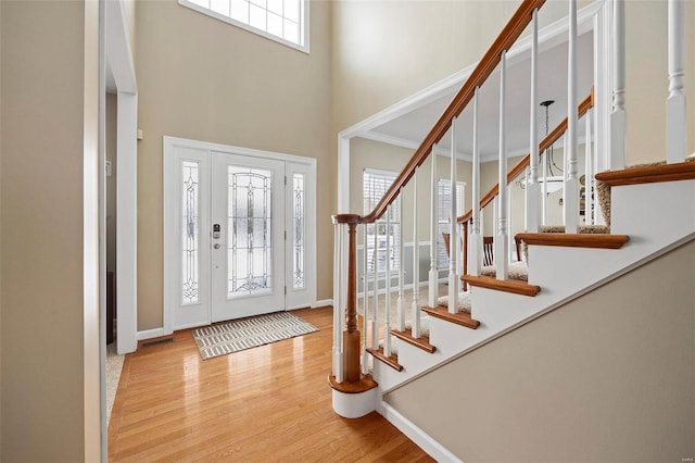 entrance foyer featuring a towering ceiling and light wood-type flooring