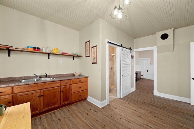 kitchen featuring light wood-type flooring, a barn door, hanging light fixtures, and sink