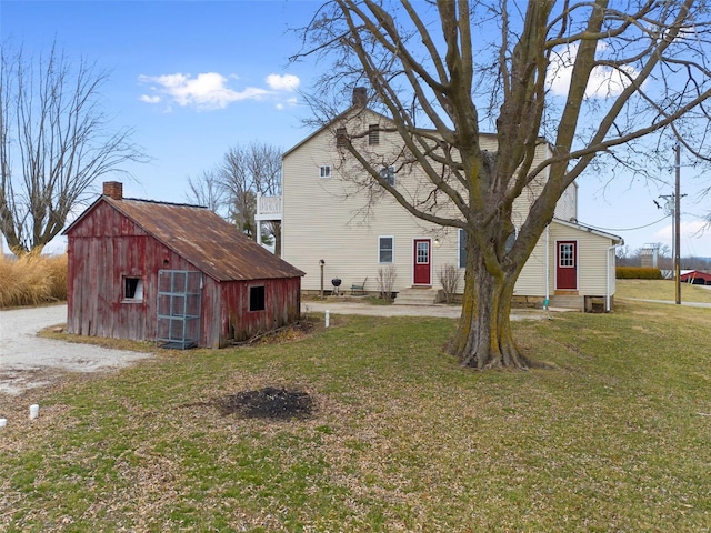 rear view of property featuring a shed and a lawn