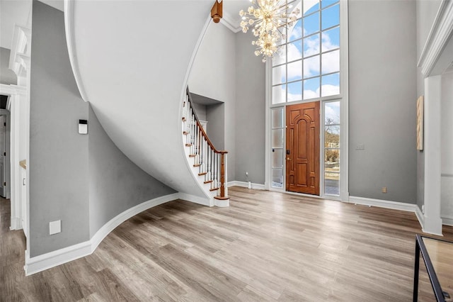 foyer entrance with light hardwood / wood-style floors, a high ceiling, a wealth of natural light, and a notable chandelier