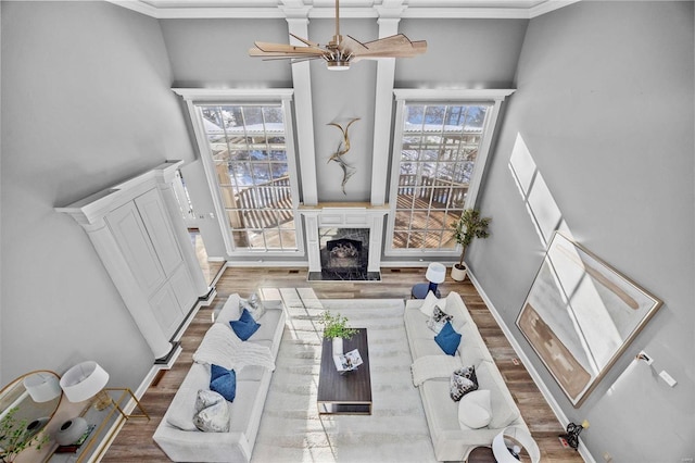 living room with ceiling fan, hardwood / wood-style floors, a fireplace, and crown molding