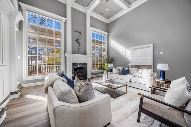 living room with a towering ceiling, beamed ceiling, a fireplace, coffered ceiling, and ornamental molding