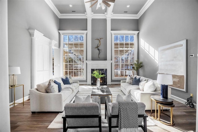 living room featuring dark hardwood / wood-style flooring, a tile fireplace, ornamental molding, and ceiling fan