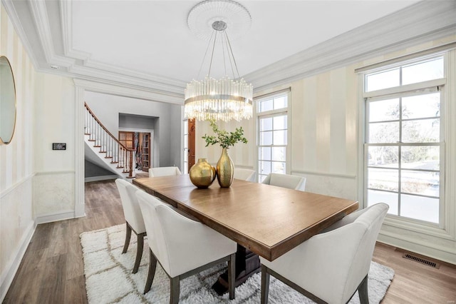 dining room with crown molding, light wood-type flooring, and a chandelier