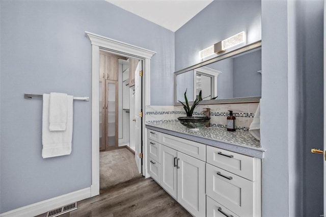 bathroom featuring decorative backsplash, wood-type flooring, and vanity